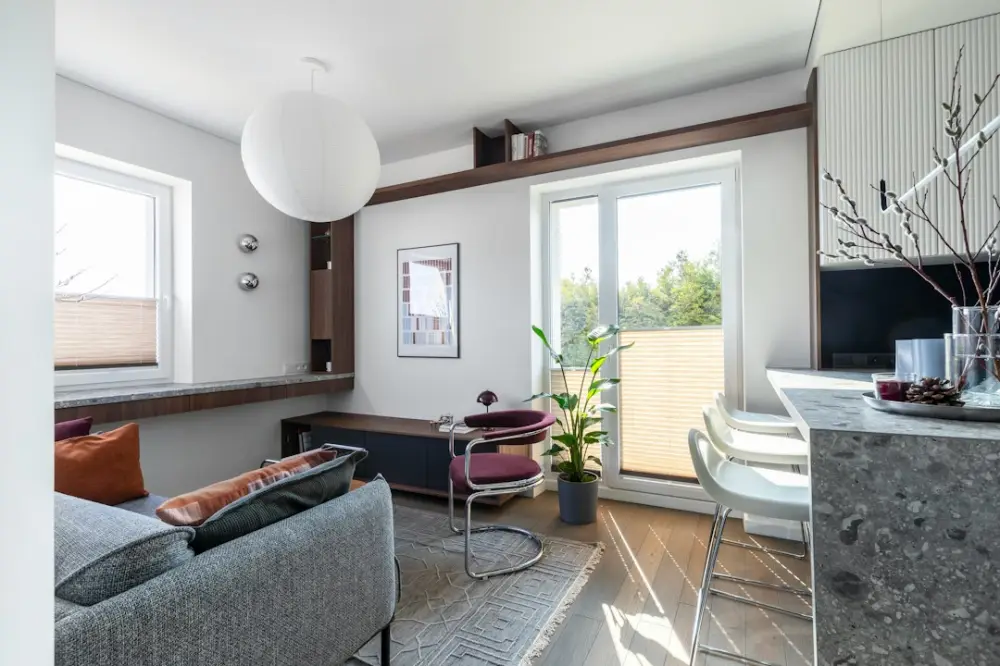 Sunny modern apartment living room with balcony and kitchen counter, illustrating compact and practical spaces